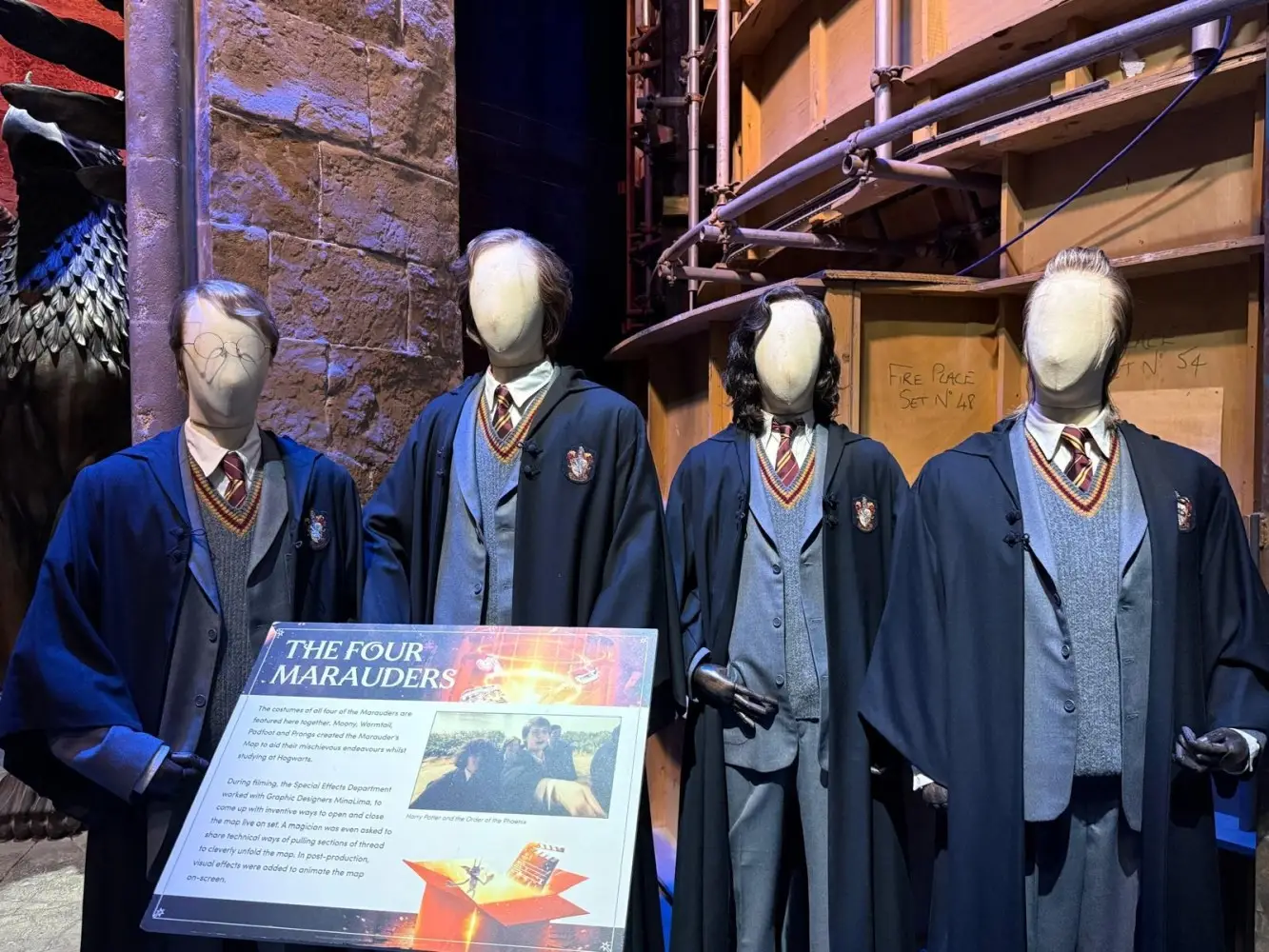 Four mannequins dressed in Hogwarts school uniforms and cloaks, representing the Marauders era characters, displayed with an informational sign in front.
