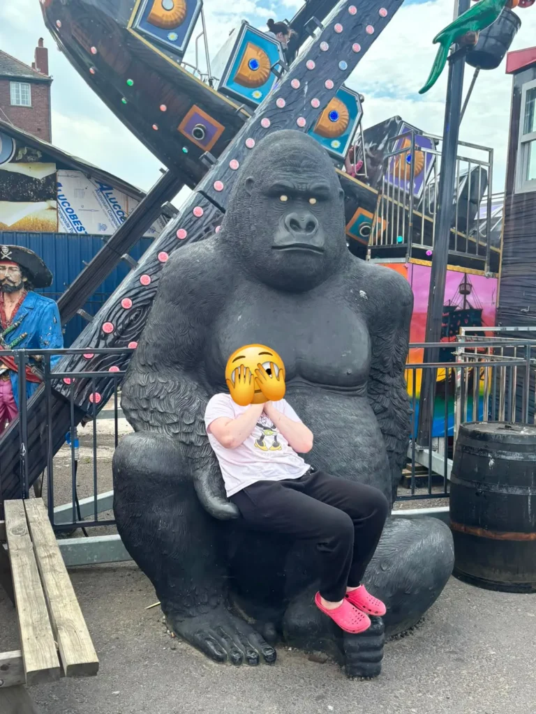 Young person posing for a photo beside a gorilla display at Barry Island.