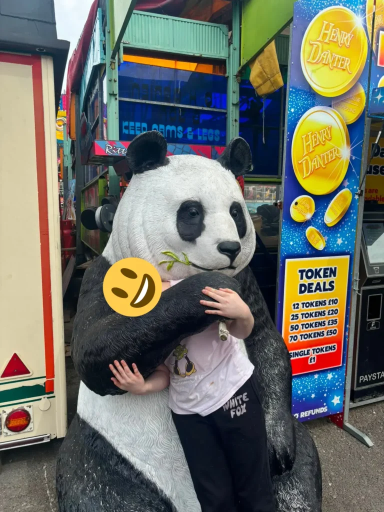 Young person posing with a panda display at Barry Island.