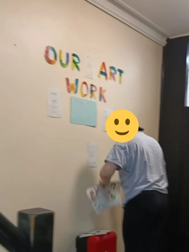 Young person independently placing artwork on a community art wall display.