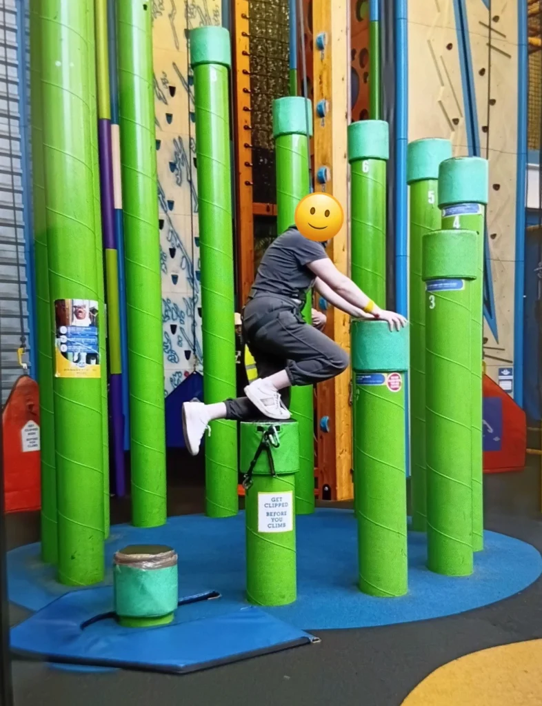 Individual navigating Clip ’n Climb balance pillars during an indoor climbing activity focused on confidence and coordination.