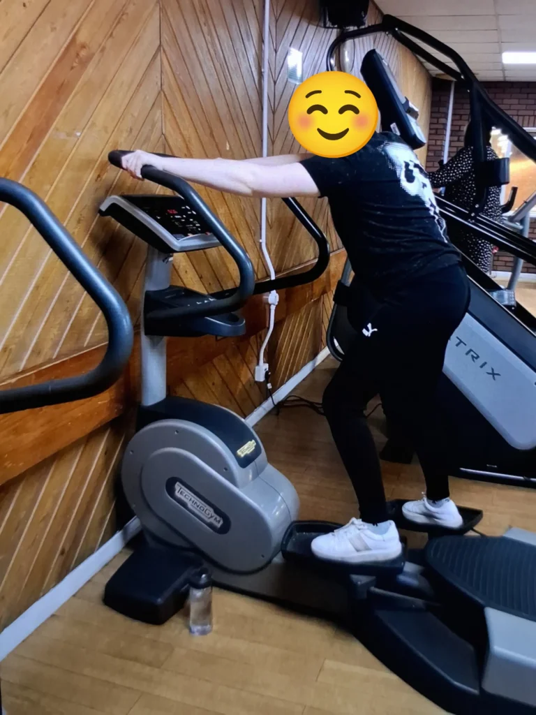 Young person exercising on a cross trainer during a fitness session at the gym.