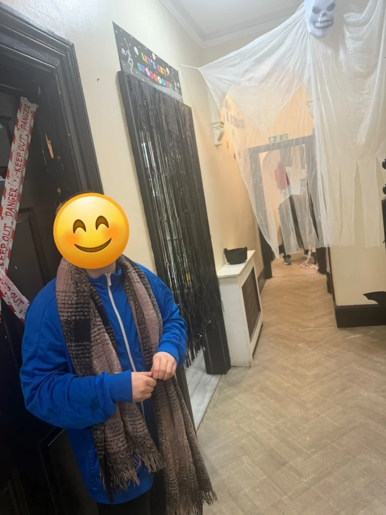 Young person standing beside Halloween decorations in a residential care home