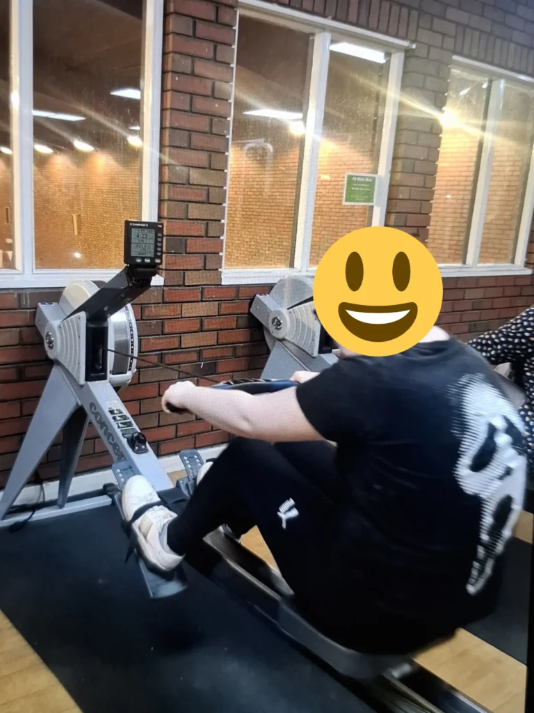 Young person using a rowing machine during a gym session to improve fitness, strength and overall wellbeing.